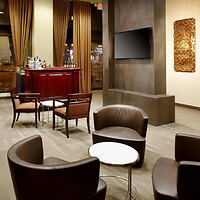 An elegant hotel lobby lounge with modern furnishings and a large flat-screen TV on the wall.